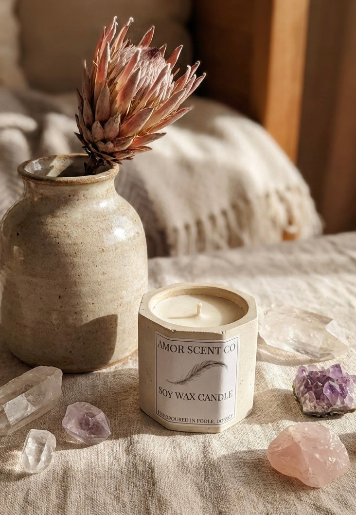 Amor Scent Co Candle with a decorative vase and crystals on a textured surface.