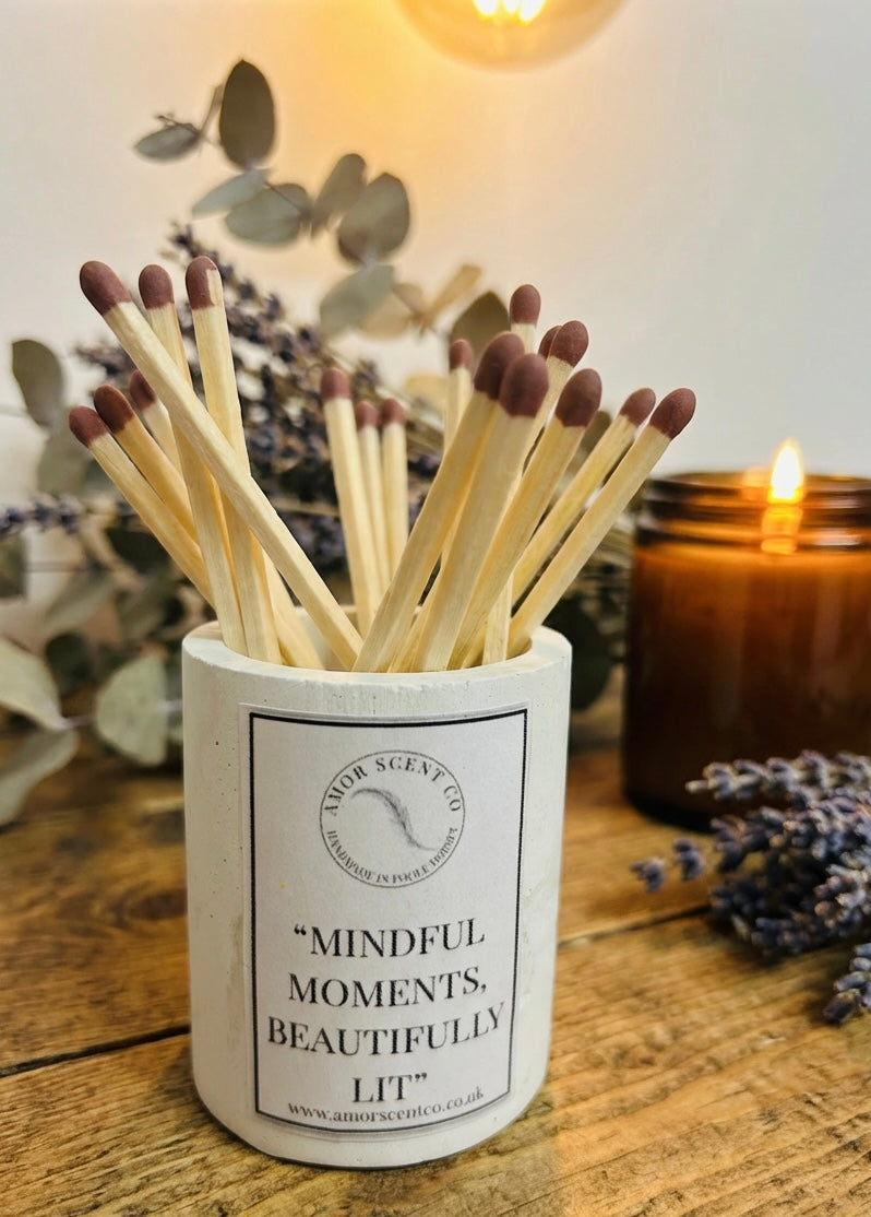 Matches in a container with a candle and lavender flowers on a wooden surface. Amor Scent Co