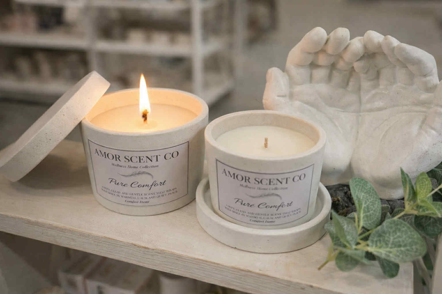 Two candles from Amor Scent Co on a shelf with decorative elements.
